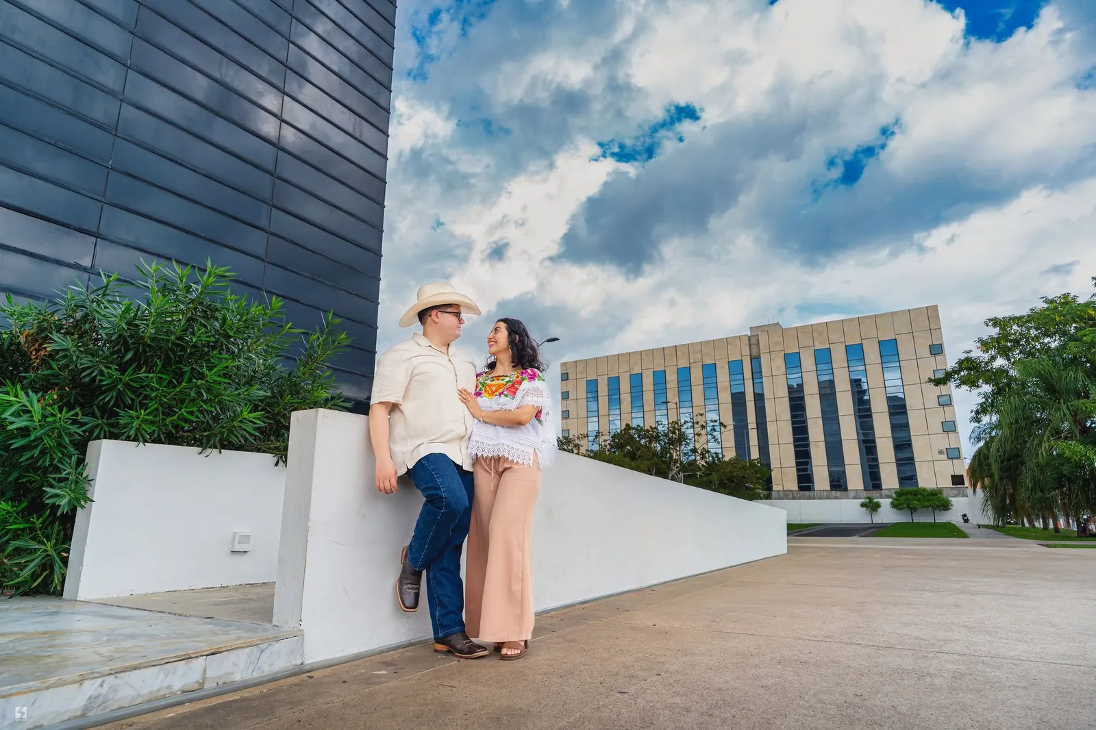 Pareja junto a un muro blanco con edificios al fondo