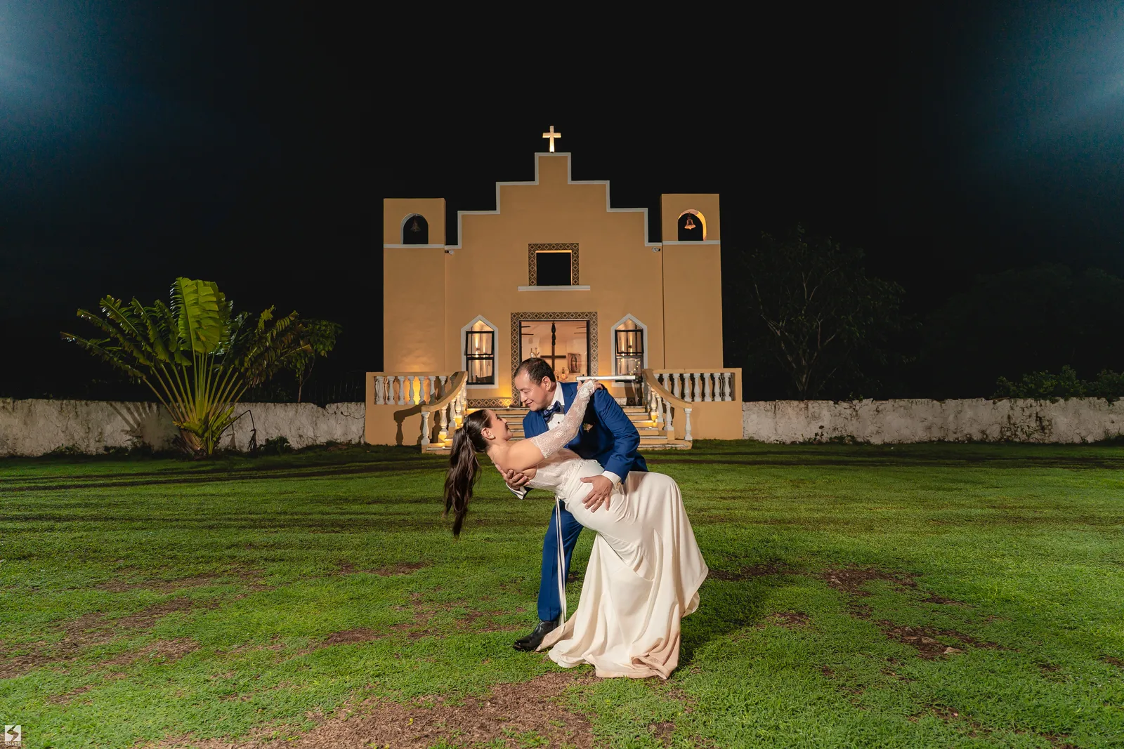 Novios bailando de noche frente a la capilla
