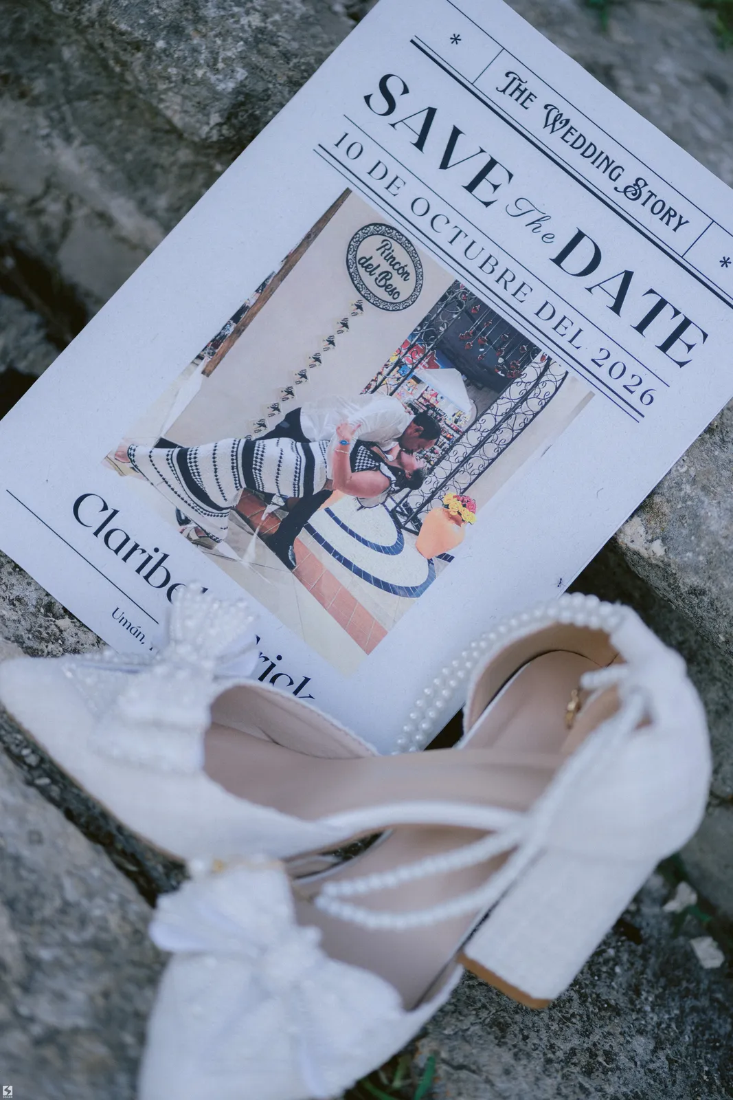 Tarjeta Save the Date y zapatos de novia sobre piedra