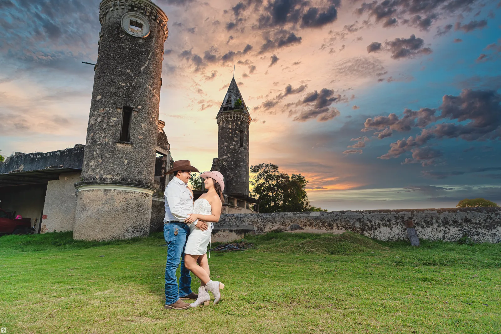 Pareja abrazada al atardecer junto a una torre antigua