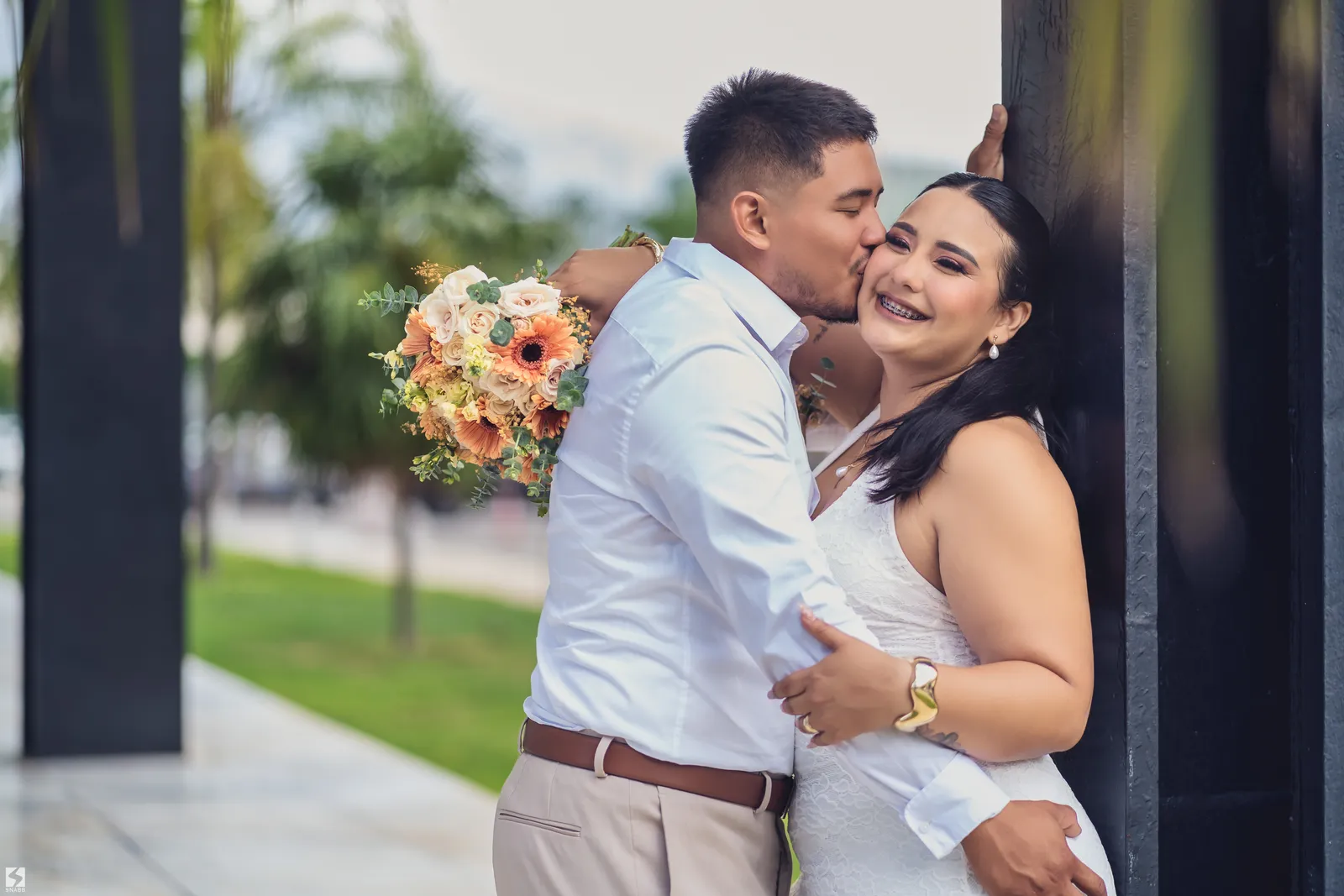Novios abrazados con un ramo de flores naranjas